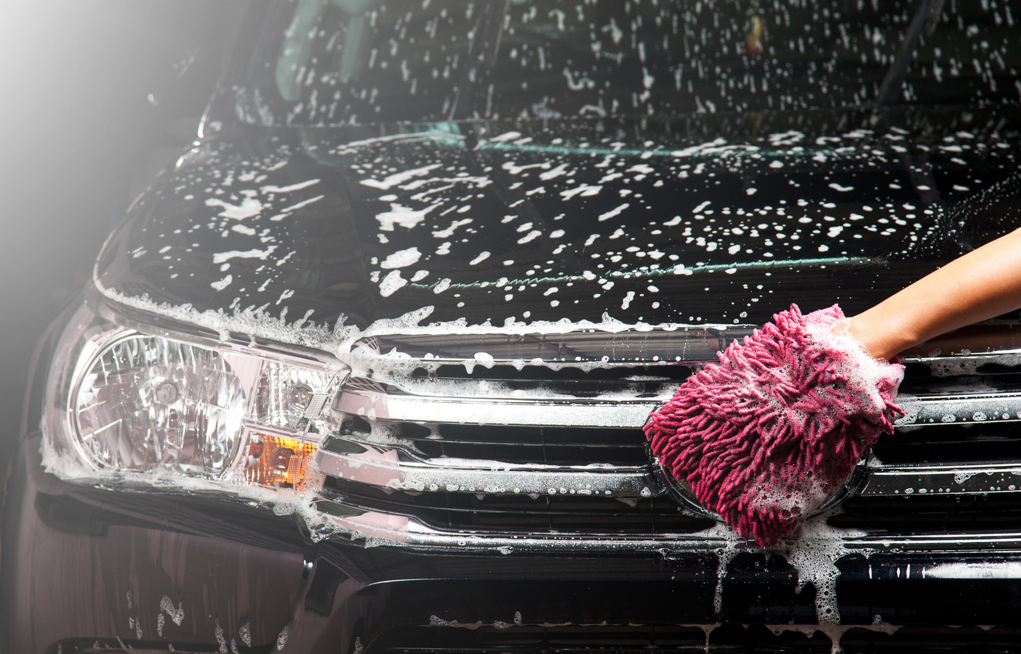 A wash mitt working carefully across a vehicle's exterior