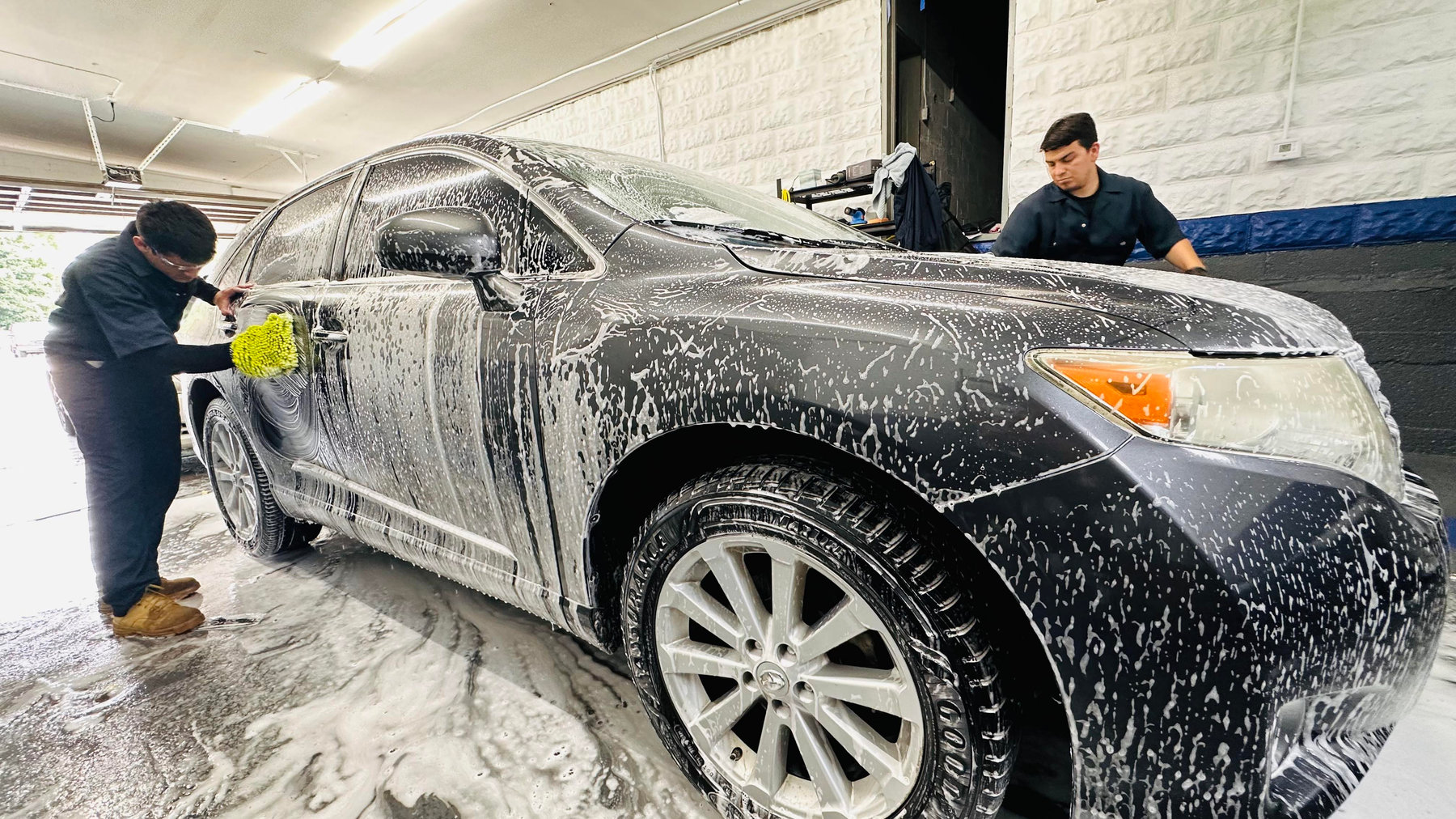 The NelMany team washing a vehicle together at the shop